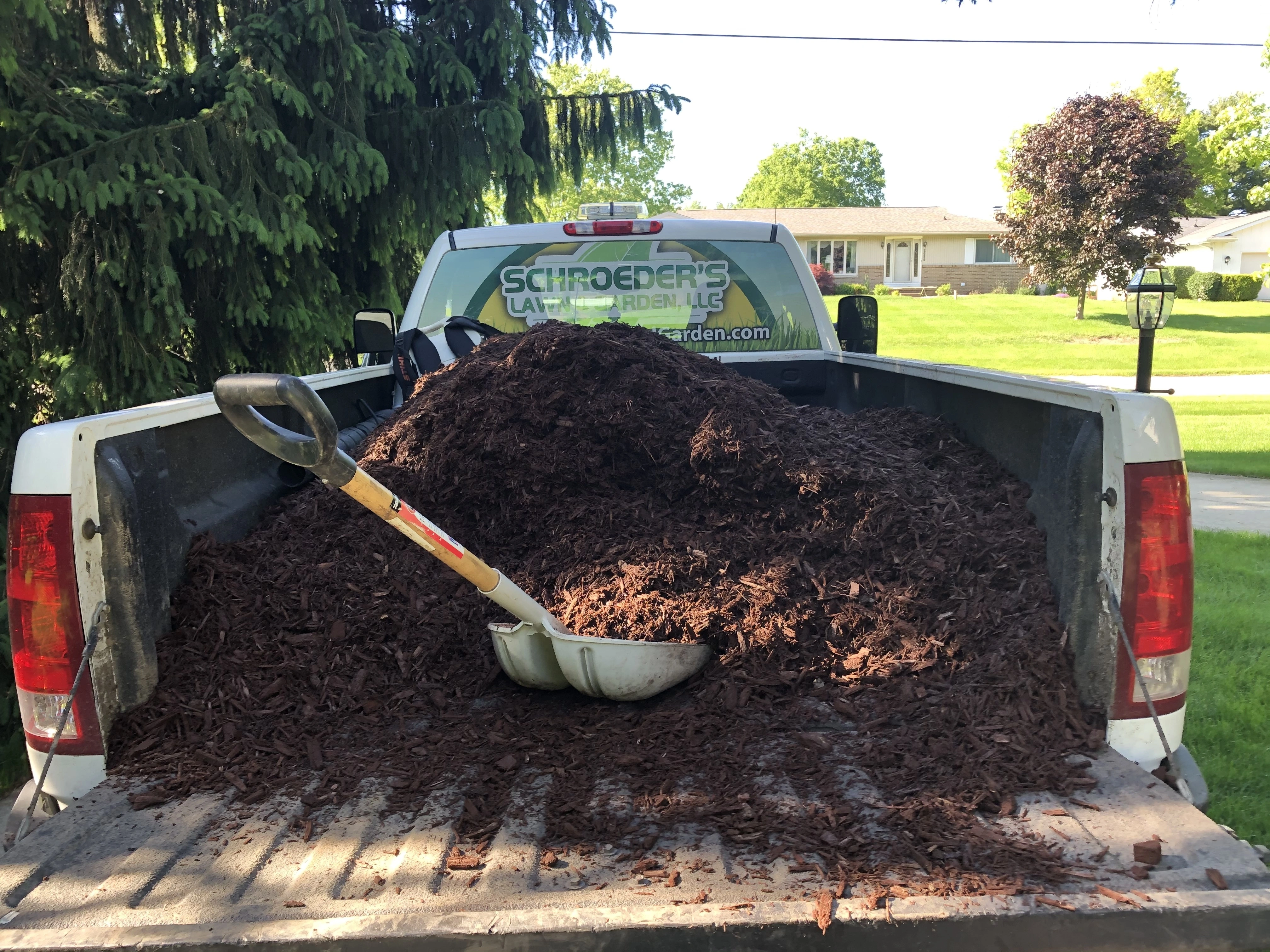 New mulch being laid in landscape bed at Lenawee home.